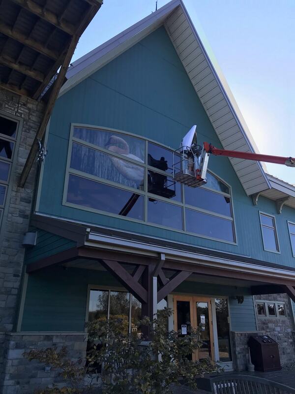 Photo: Image 360 installs a trumpeter swan window film on the back of the Visitor Center 